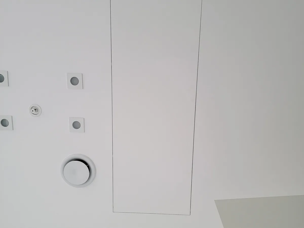 Concealed access door in the ceiling next to a round air conditioning diffuser